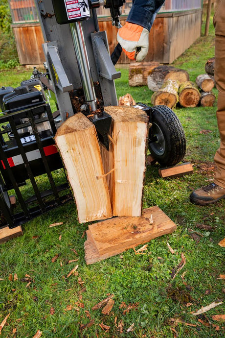 A thick, freshly cut log being vertically split by the gray Oregon 3000 Series 30-ton log splitter in a grassy area.